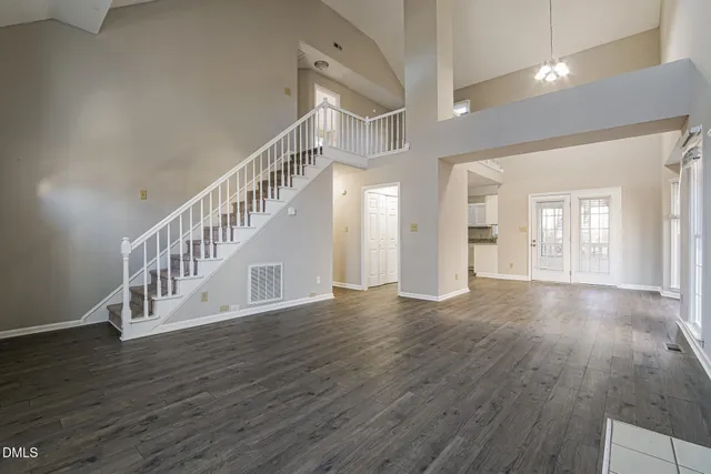 an empty room with wooden floor fireplace and windows