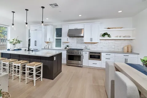 a kitchen with stainless steel appliances a stove a sink dishwasher a oven with white cabinets and wooden floor