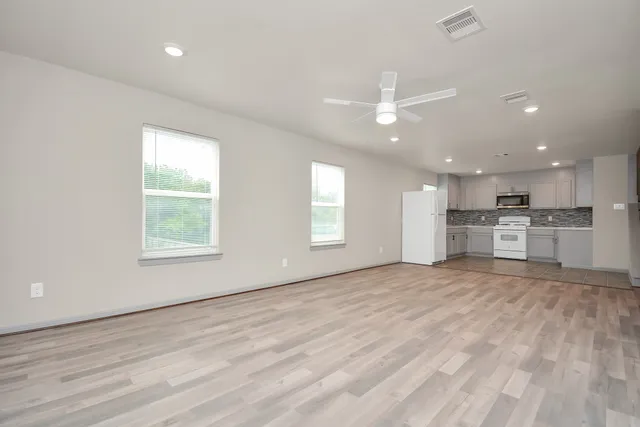 a view of an empty room with kitchen appliances and a window