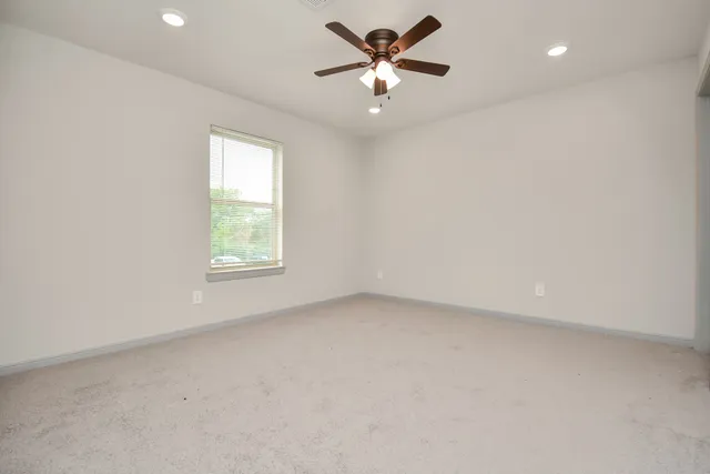 an empty room with a window and a fan
