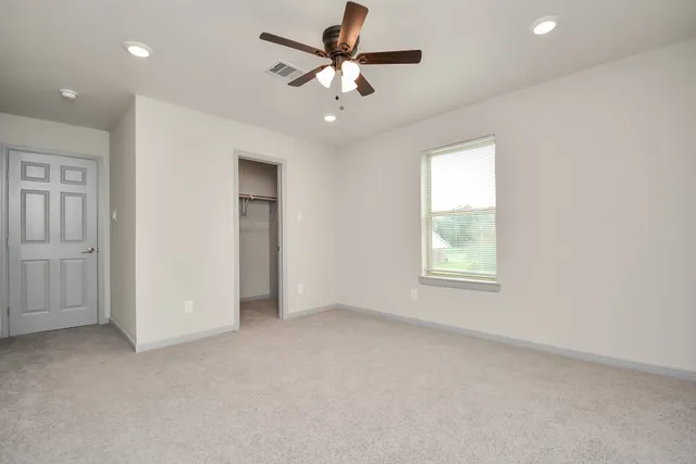 an empty room with fan and windows