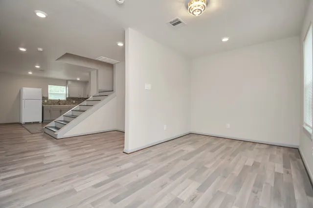 a view of a livingroom with wooden floor and staircase