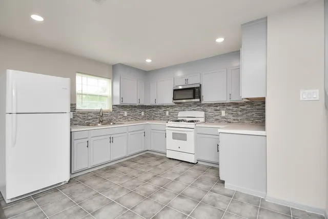 a kitchen with granite countertop white cabinets and white appliances