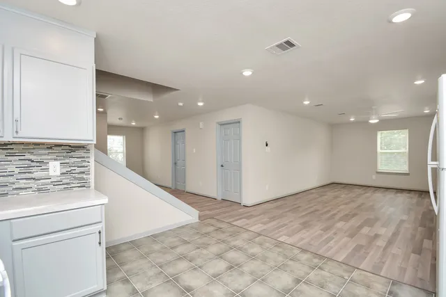 a view of an empty room and a kitchen