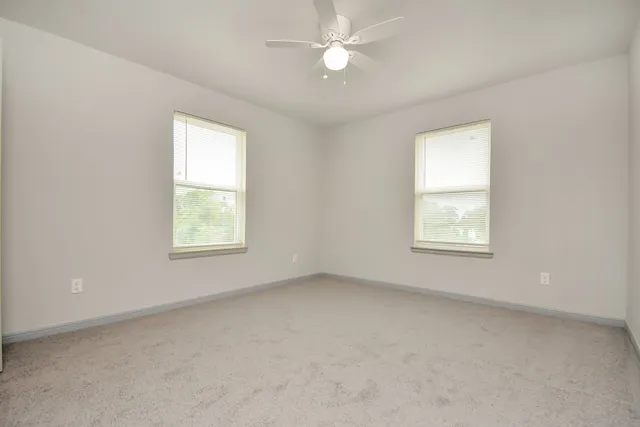 an empty room with a window and a fan