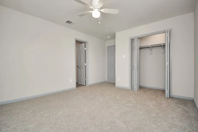 an empty room with closet and a ceiling fan