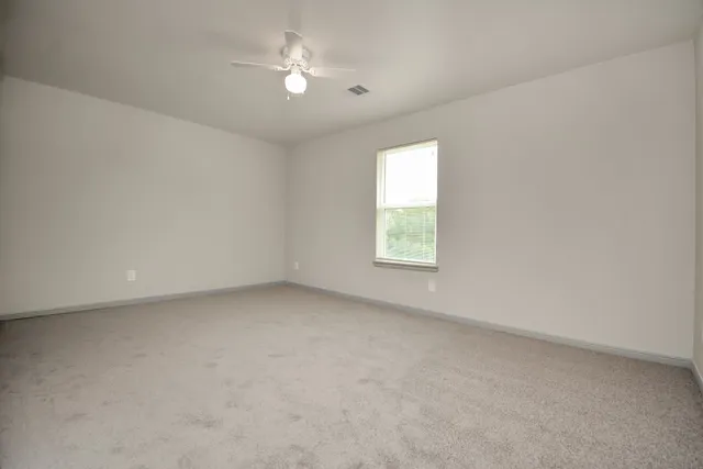 an empty room with a window and a ceiling fan