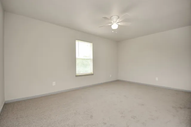 an empty room with a window and a ceiling fan