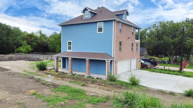 a view of a house with a yard plants and large tree