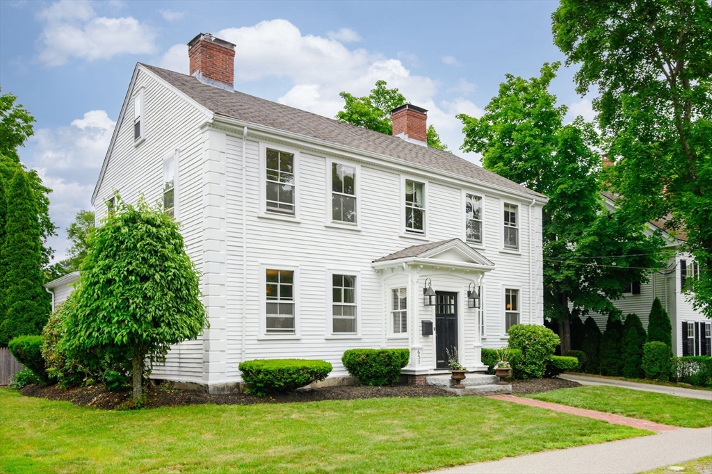 a front view of a house with a yard and trees