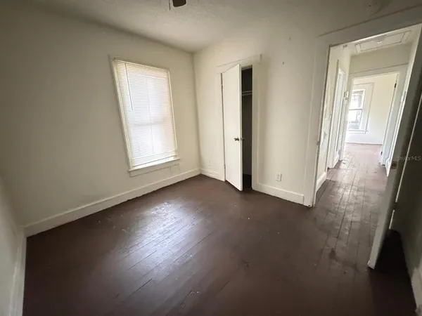 an empty room with wooden floor and windows