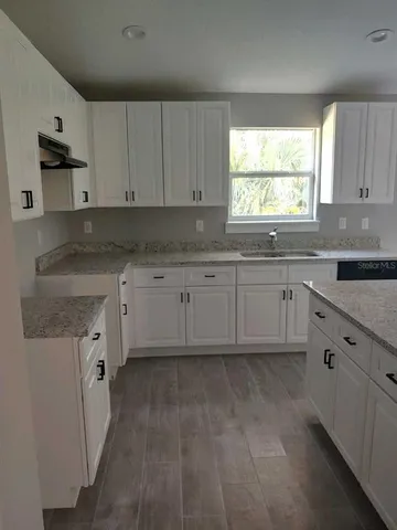 a kitchen with granite countertop white cabinets white appliances with a sink and dishwasher