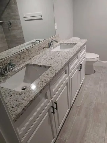 a bathroom with a granite countertop sink and a toilet