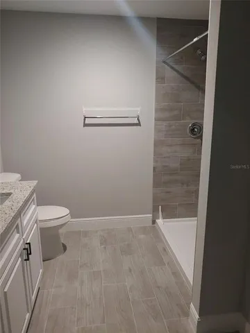 a bathroom with a granite countertop toilet and a shower