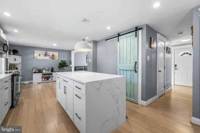 a large kitchen with a large counter top a sink a refrigerator and cabinets