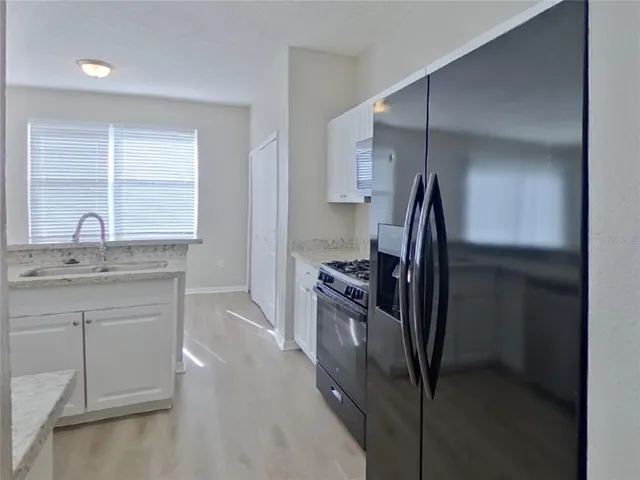 a kitchen with granite countertop a refrigerator and a sink