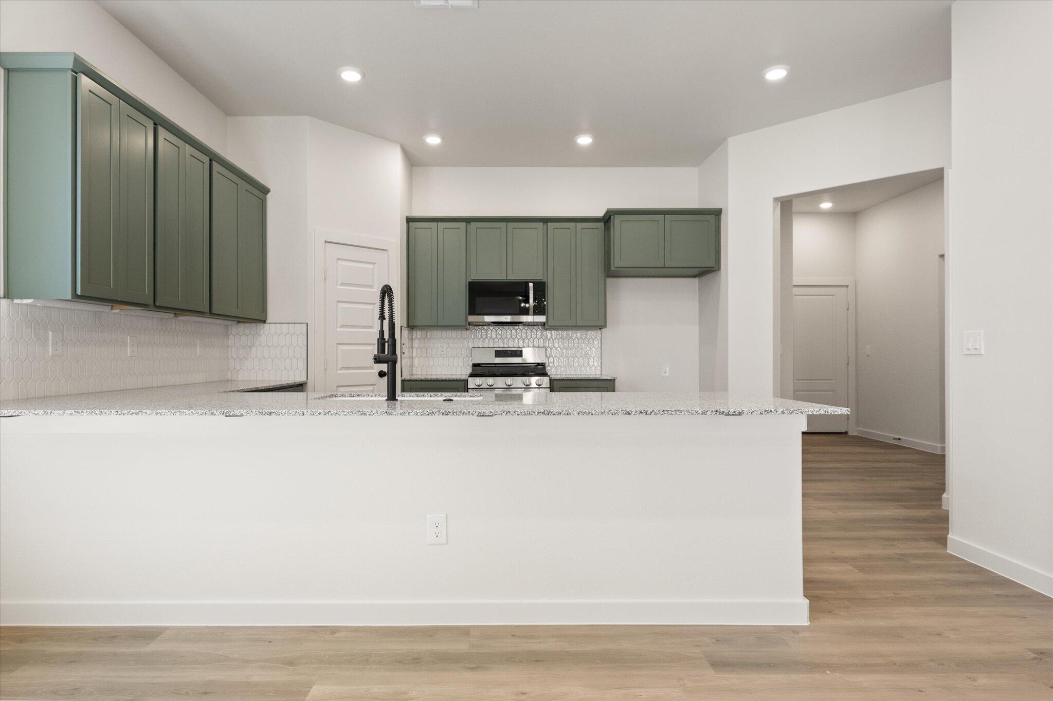 7003 53rd Street Lubbock, TX 79407 - Photo 8 of 25 a large kitchen with stainless steel appliances a large counter top a stove and a refrigerator