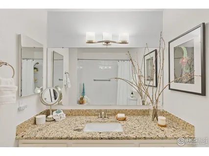 a bathroom with a granite countertop sink a mirror and shower
