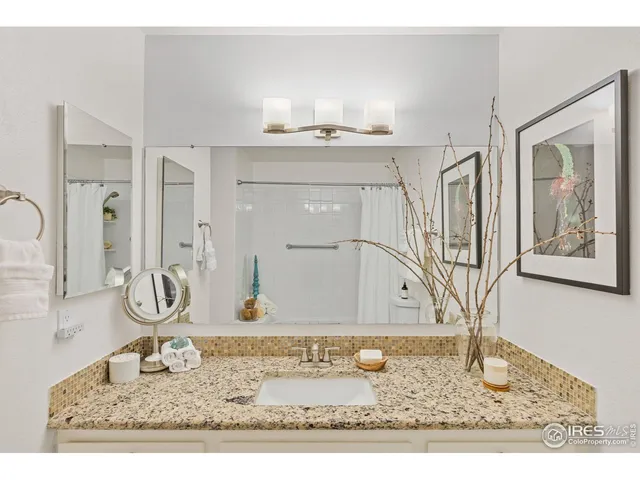 a bathroom with a granite countertop sink a mirror and shower
