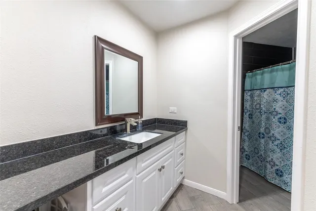 a bathroom with a granite countertop sink and a mirror