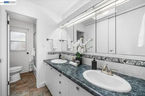 a bathroom with a granite countertop sink a toilet and a mirror