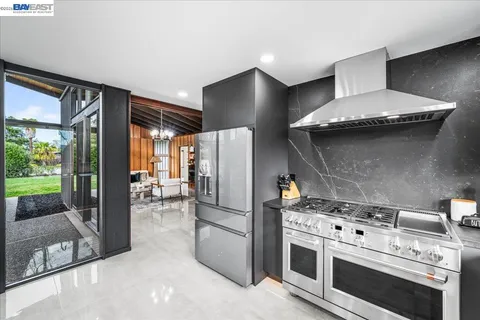 a kitchen with stainless steel appliances granite countertop a stove a refrigerator and a fireplace with the wooden floor