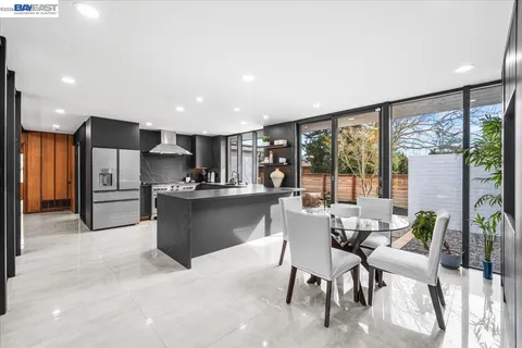 a kitchen with stainless steel appliances kitchen island granite countertop a refrigerator and a dining table