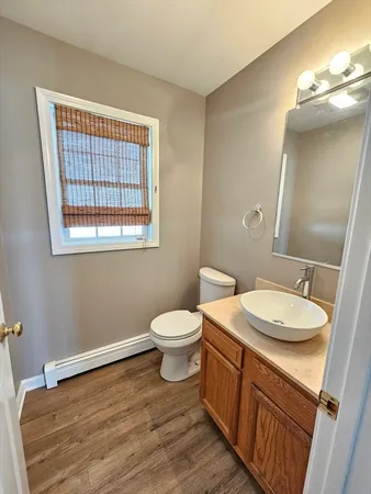 a bathroom with a granite countertop toilet a sink a mirror and a window