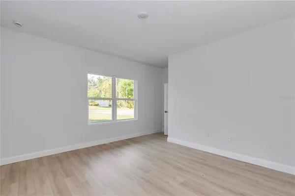 an empty room with wooden floor and window