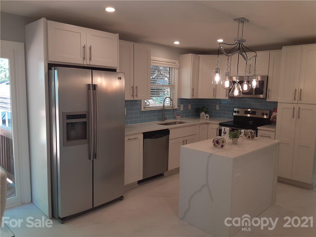 1501 Tyvola Road Charlotte, NC 28210 - Photo 2 of 20 a kitchen with kitchen island granite countertop a sink cabinets and stainless steel appliances