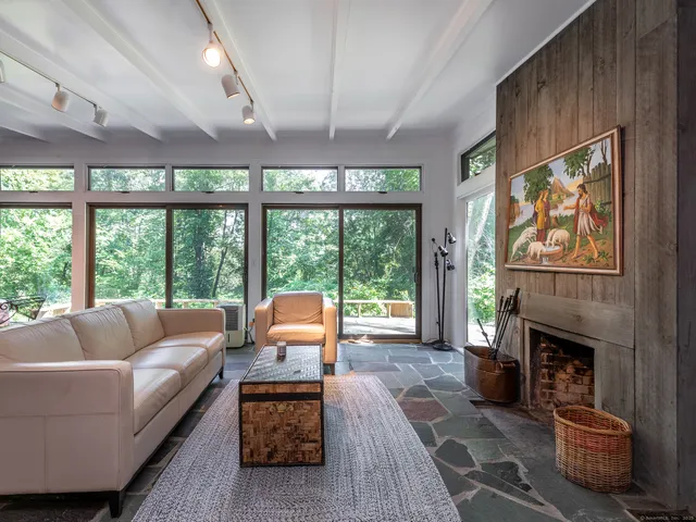 a living room with furniture a floor to ceiling window and a fireplace