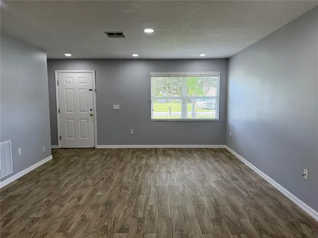 an empty room with wooden floor and windows