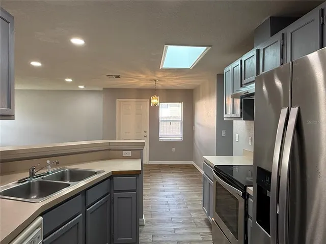 a kitchen with stainless steel appliances granite countertop a sink and a refrigerator