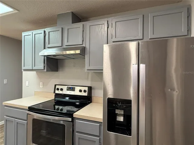 a kitchen with stainless steel appliances granite countertop a refrigerator a stove and a sink