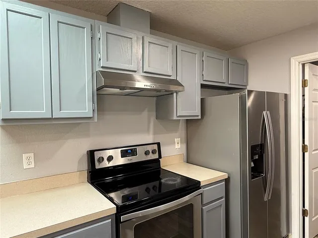 a kitchen with stainless steel appliances granite countertop a stove a refrigerator and a microwave