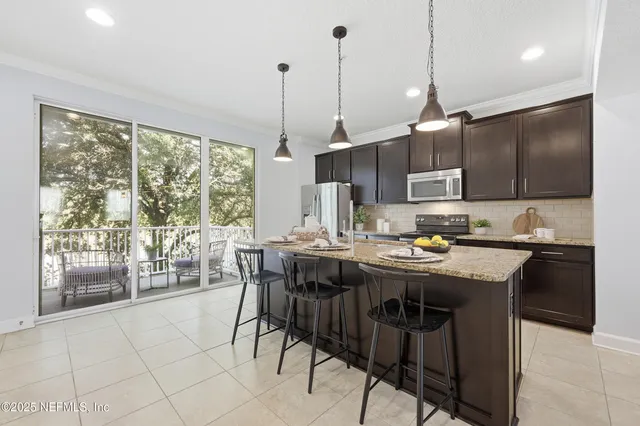 a kitchen with kitchen island a stove a refrigerator a sink a dining table and chairs with wooden floor