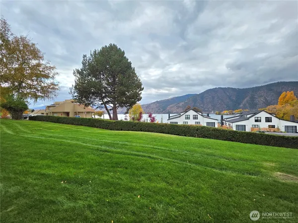 a view of a house with a big yard and large trees