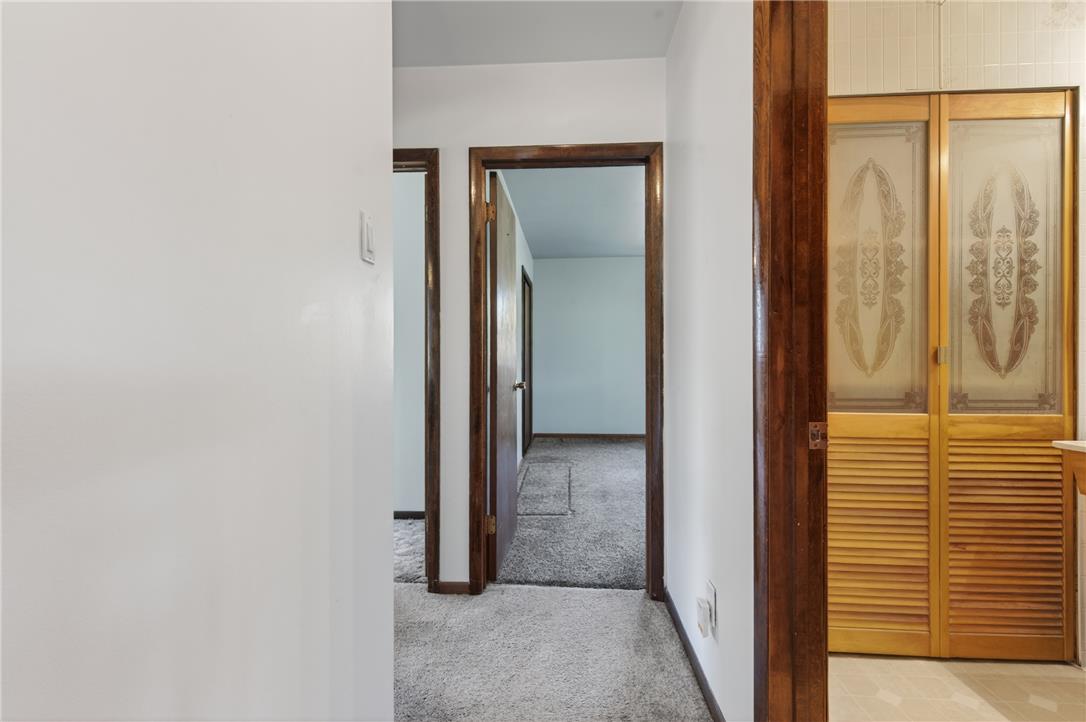 62 Stoney Road Tamaqua, PA 18252 - Photo 27 of 61 A well-lit interior hallway leads to multiple rooms, showcasing warm wooden doorframes and practical carpet flooring.