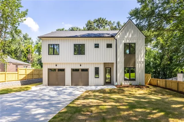 a view of yellow house with small yard plants and large tree