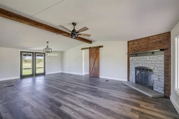 a view of an empty room with wooden floor fireplace and a window