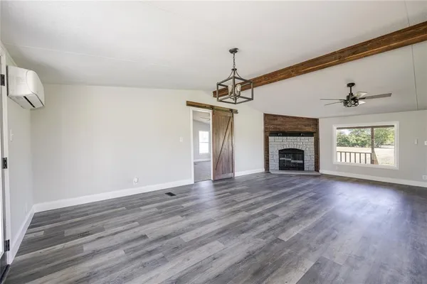 a view of empty room with wooden floor fireplace and a window