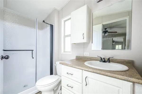 a bathroom with a granite countertop sink toilet a mirror and shower