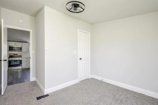 an empty room with kitchen space and wooden floor