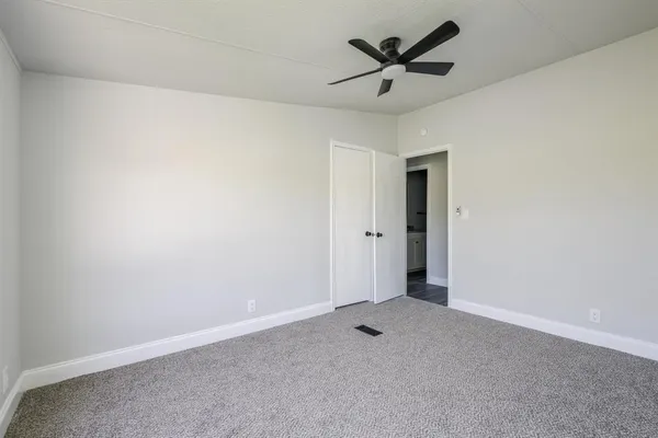 an empty room with closet and a ceiling fan