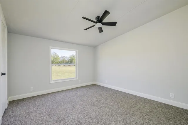 an empty room with a ceiling fan and windows