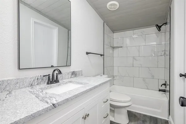 a bathroom with a granite countertop sink toilet and shower