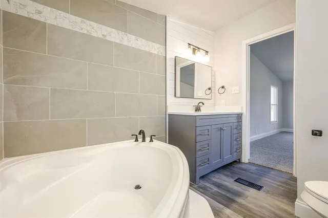 a bathroom with a tub sink and mirror