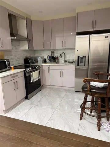 a kitchen with granite countertop a stove a sink dishwasher a refrigerator and cabinets with wooden floor