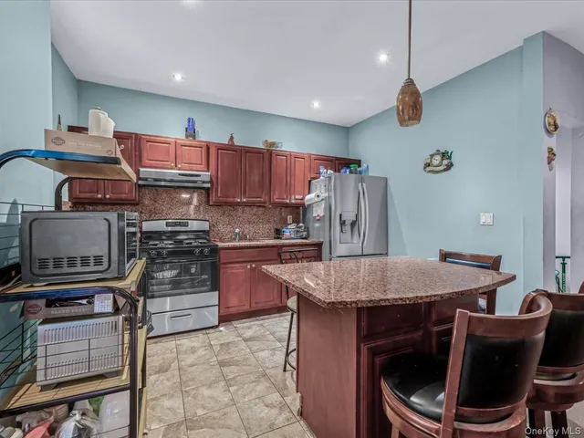 a kitchen with stainless steel appliances granite countertop a stove top oven a sink and a refrigerator