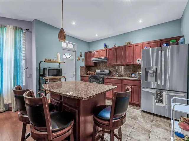 a kitchen with stainless steel appliances granite countertop a stove refrigerator a sink dishwasher a dining table and chairs